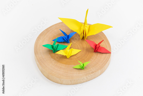 Colorful paper cranes placed on a wooden plate. top view