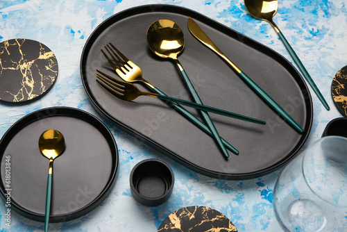 Clean plates with golden cutlery on blue grunge table
