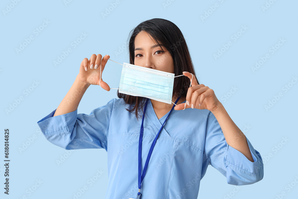 Female Asian medical intern with mask on blue background Female Asian medical intern with mask on blue background