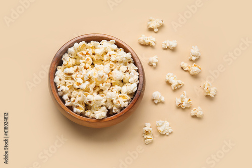 Bowl with tasty popcorn on beige background