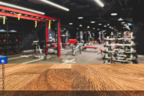 Empty old wooden table in front of blurred background of interior in the gym and fitness center and weight training equipment. Can be used for display or montage for show your products.