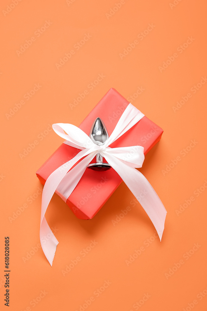 Gift box with anal plug on orange background Gift box with anal plug on orange background