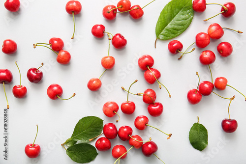 Many sweet cherries and leaves on white background