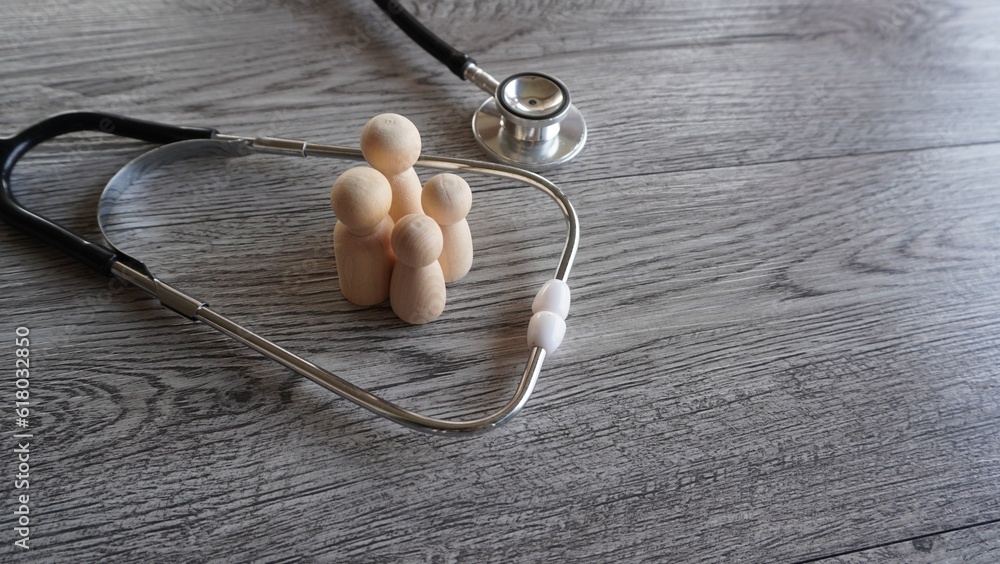 Stethoscope and family wooden dolls with copy space. Family healthcare and medical insurance concept Stethoscope and family wooden dolls with copy space. Family healthcare and medical insurance concept