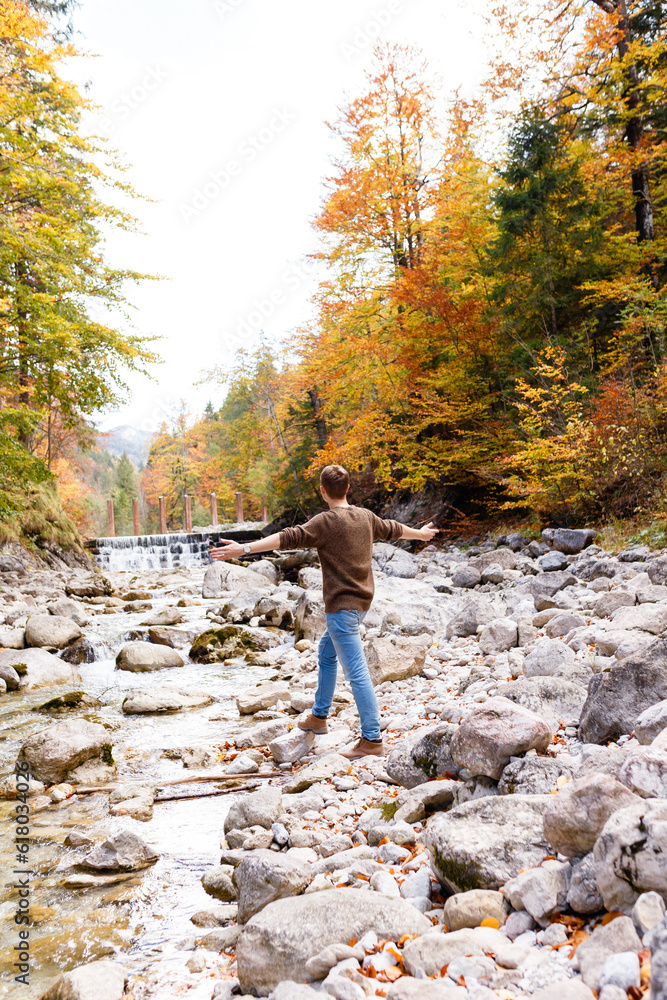 man near a mountain river in the forests of the Alps
