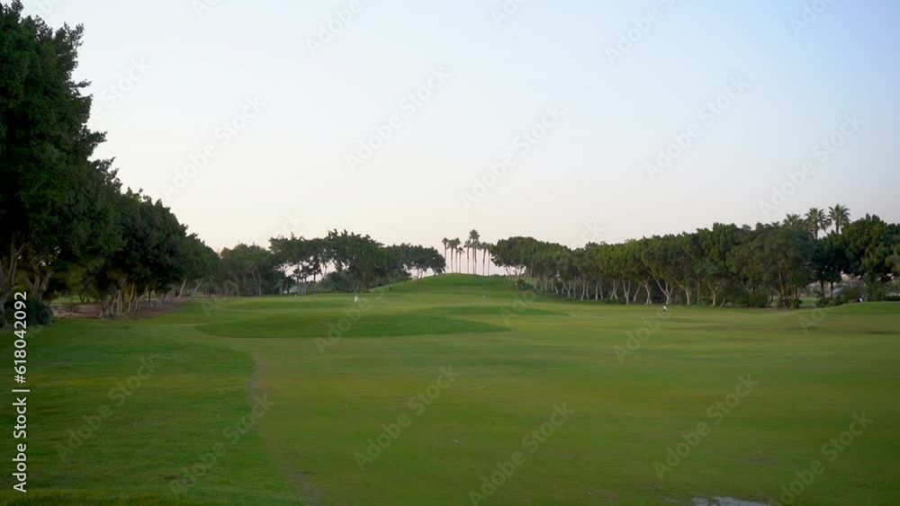 A beautiful golf course with green grass, trees, lake and feather grass on a sunny day. A beautiful golf course with green grass, trees, lake and feather grass on a sunny day.