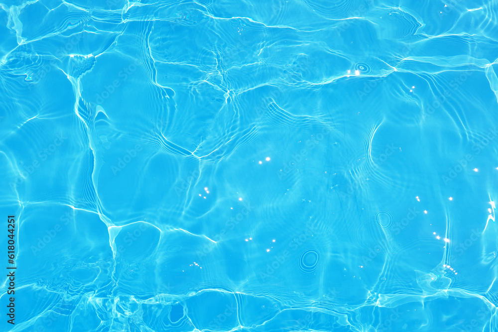 Blue water with ripples on the surface. Defocus blurred transparent blue colored clear calm water surface texture with splashes and bubbles. Water waves with shining pattern texture background.