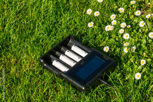 Foto Black AA battery charger with rechargeable alkaline batteries  on the grass