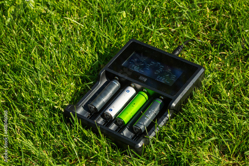 Schilderij op canvas Black AA battery charger with rechargeable alkaline batteries  on the grass