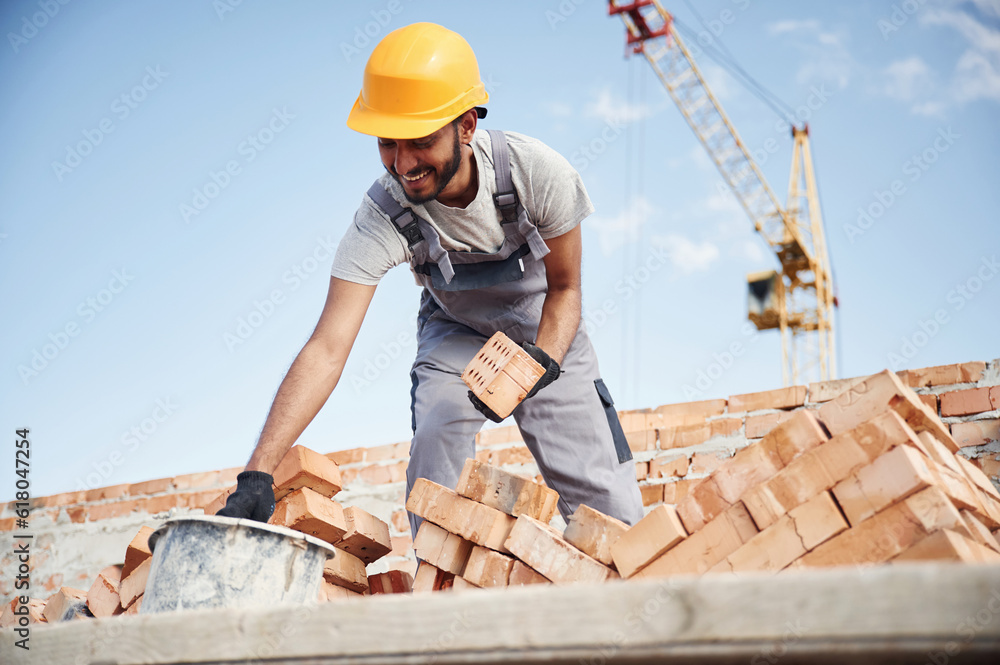 Blue sky and crane is behind. Handsome Indian man is on the construction site Blue sky and crane is behind. Handsome Indian man is on the construction site