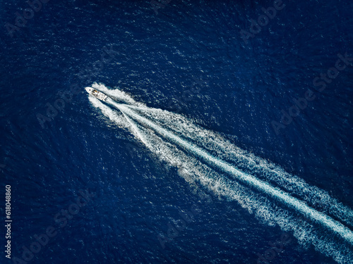 Obraz na płótnie High aerial view of a motor speeboat traveling over blue ocean and leaving a trail of fom and bubbles w salonie