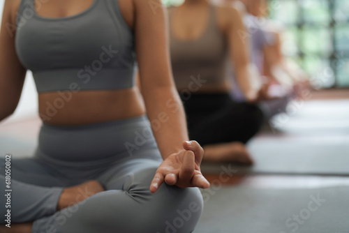 Young Asian women practice relaxing meditation lotus pose on a yoga mat in a fitness center.