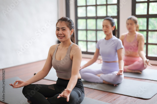 Groups of young sporty women practicing basic yoga positions, lotus pose on yoga mat at yoga class to improve physical and mental health © Somkiat