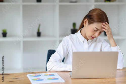 An Asian frustrated exhausted business woman sitting in front of a laptop for a long time, concept office syndrome.