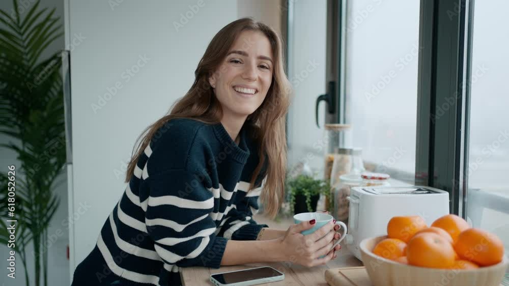 Video of beautiful young woman drinking coffee while looking at camera in the kitchen at morning Video of beautiful young woman drinking coffee while looking at camera in the kitchen at morning