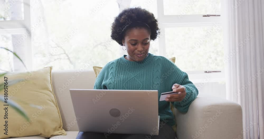 Happy african american woman making payment using credit card and laptop at home, slow motion Happy african american woman making payment using credit card and laptop at home, slow motion