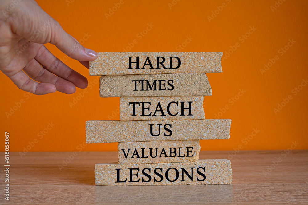 Lesson from hard times symbol. Concept words Hard times teach us valuable lessons on brick blocks on a beautiful orange background. Businessman hand. Business lesson from hard times concept.