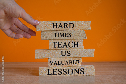 Obraz na płótnie Lesson from hard times symbol. Concept words Hard times teach us valuable lessons on brick blocks on a beautiful orange background. Businessman hand. Business lesson from hard times concept. w salonie