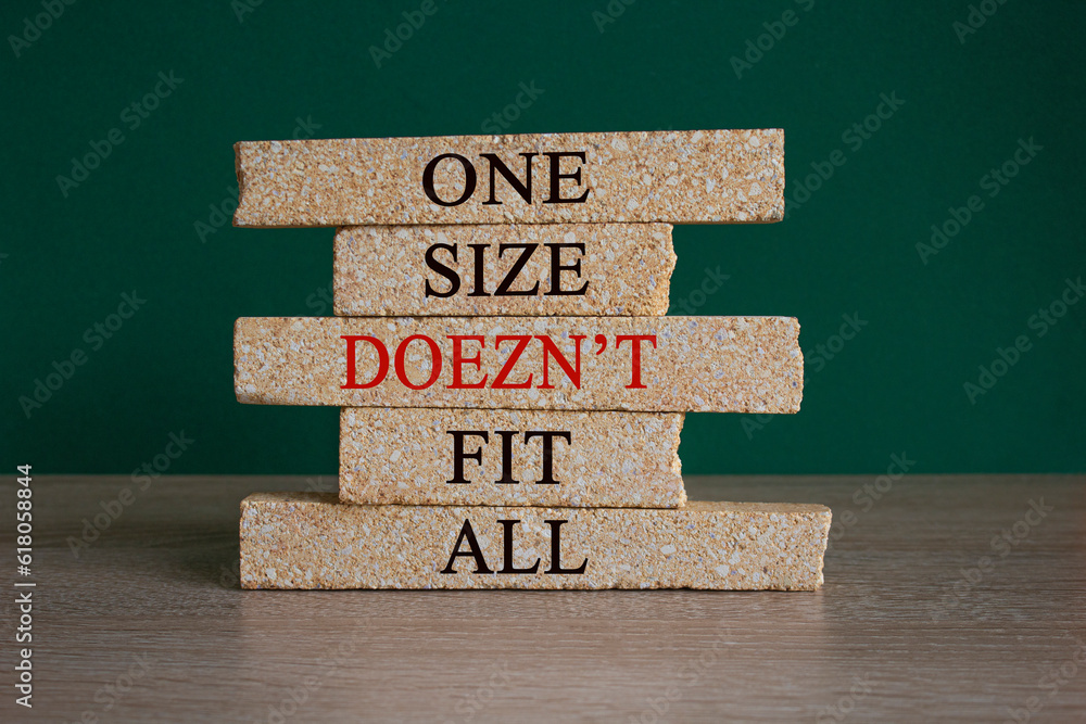 Concept red words One size does not fit all on brick blocks. Beautiful wooden table green background. One size does not fit all business concept. Copy space.