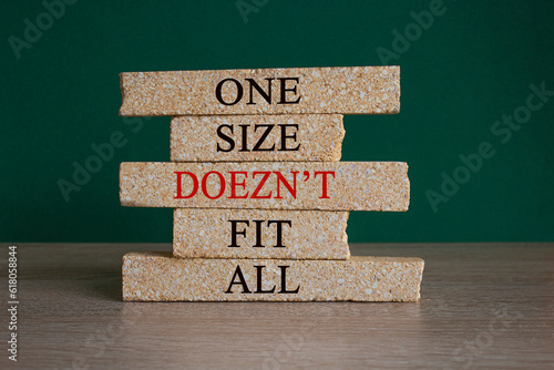 Obraz na płótnie Concept red words One size does not fit all on brick blocks. Beautiful wooden table green background. One size does not fit all business concept. Copy space. w salonie