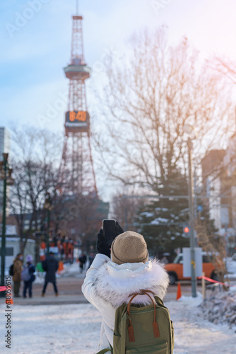 Woman tourist Visiting in Sapporo, Traveler in Sweater sightseeing Sapporo tower with Snow in winter. landmark and popular for attractions in Hokkaido, Japan. Travel and Vacation concept photo