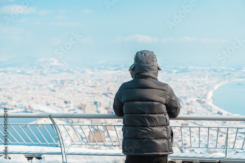 man tourist Visiting in Hakodate, Traveler in Sweater sightseeing view from Hakodate mountain with Snow in winter. landmark and popular for attractions in Hokkaido, Japan.Travel and Vacation concept photo