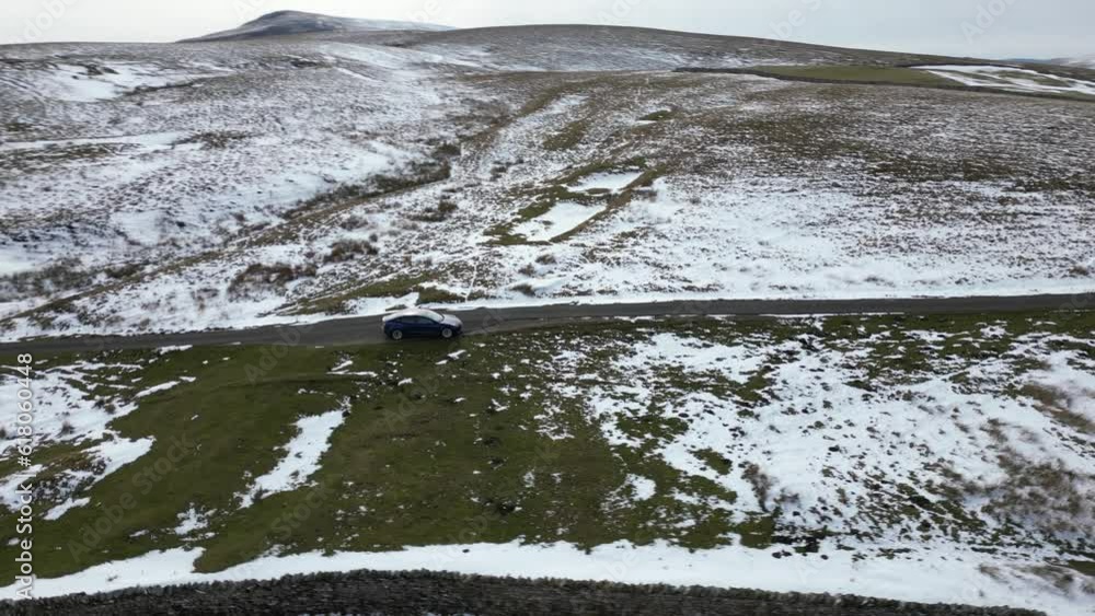 Drone shot of a car stopped on a narrow road in snowy field Drone shot of a car stopped on a narrow road in snowy field