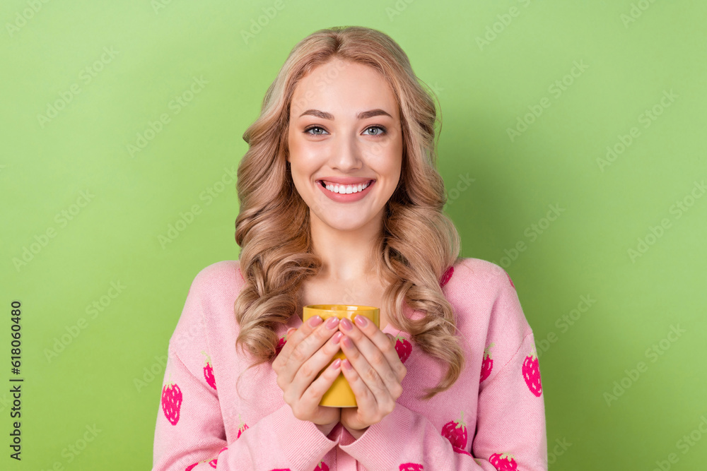Photo of peaceful adorable cheerful girl toothy smile arms hold fresh coffee cup isolated on green color background Photo of peaceful adorable cheerful girl toothy smile arms hold fresh coffee cup isolated on green color background