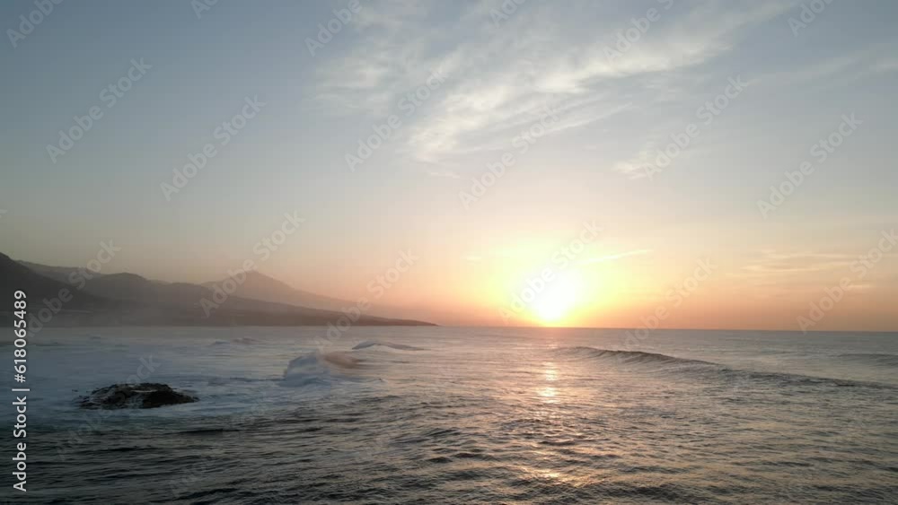 Aerial of the golden sunset shining brightly behind the calm waters of the sea Aerial of the golden sunset shining brightly behind the calm waters of the sea