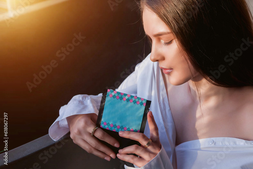Close-up of thoughtful lovely young lady holding cosmetic mask, pensive closed eyes. Face of pretty woman with mask bag in hands at bathroom. Cosmetology self care concept. Copy advertising text space