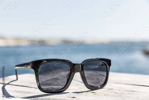 Sonnenbrille af einem Holzdeck am Strand
