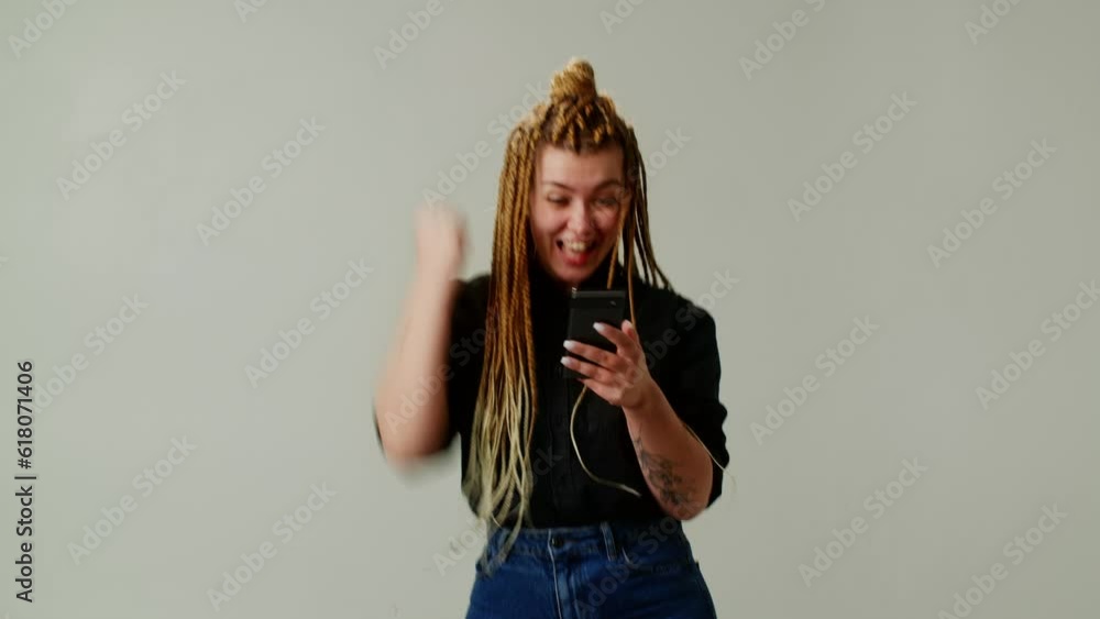 A modern girl with pigtails learned amazing news on her phone. The girl rejoices at the good news. A modern girl with pigtails learned amazing news on her phone. The girl rejoices at the good news.
