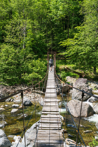Hiker walking over an old bridge in National Park Val Grande.