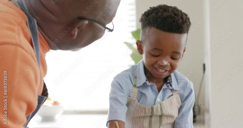 Happy african american grandfather and grandson talking, baking in kitchen, slow motion Happy african american grandfather and grandson talking, baking in kitchen, slow motion