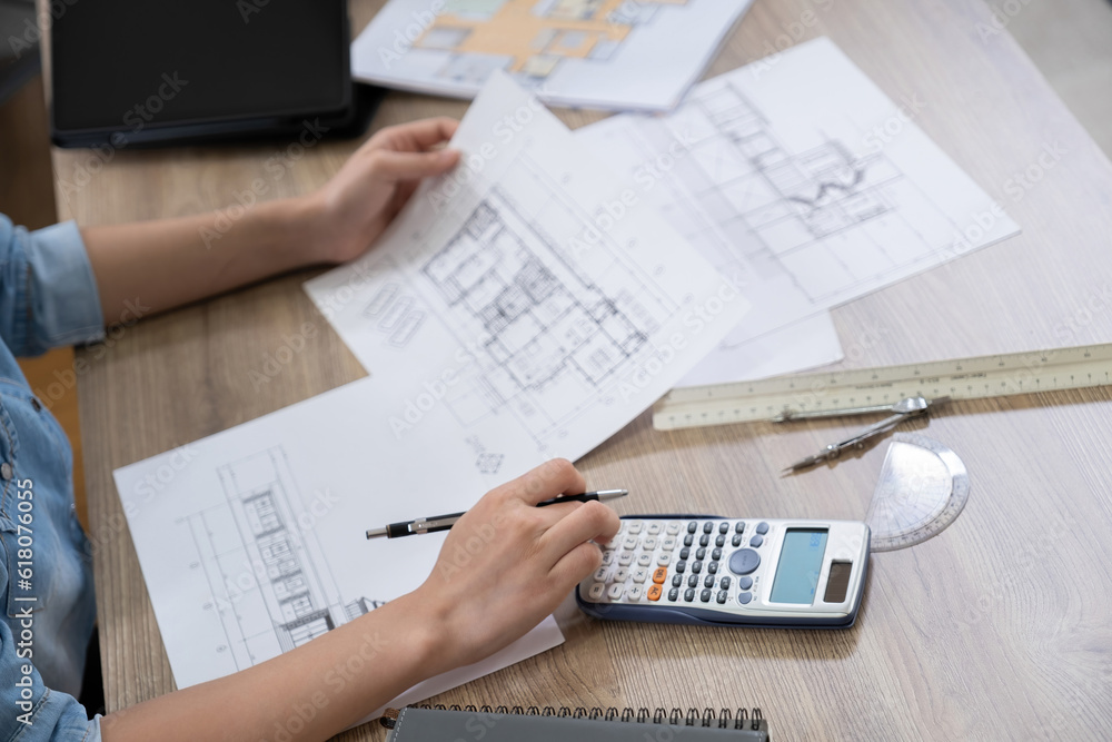 Engineers discuss a blueprint while checking information on a tablet computer in a office. Engineers discuss a blueprint while checking information on a tablet computer in a office.