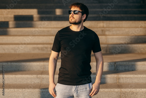 Young stylish bearded man in a black T-shirt and sunglasses. Street photo