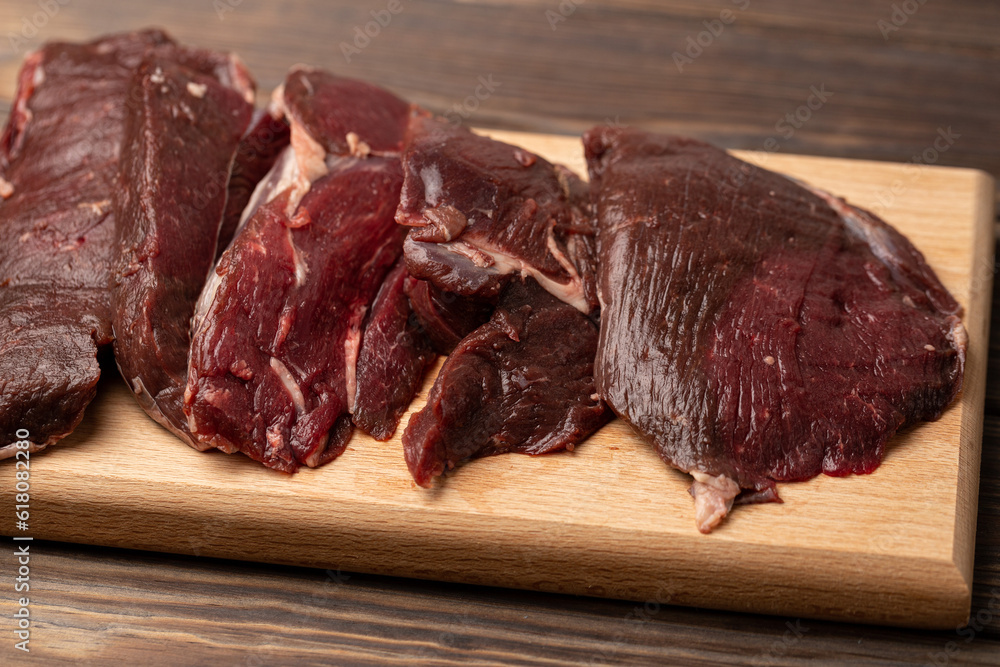 Raw fresh roe deer meat, fillet on a cutting board Raw fresh roe deer meat, fillet on a cutting board