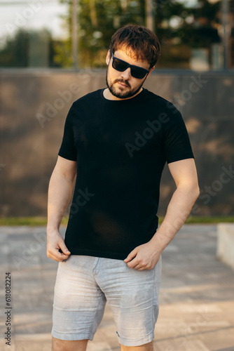 Young stylish bearded man in a black T-shirt and sunglasses. Street photo