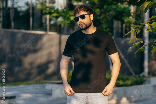 Young stylish bearded man  in a black T-shirt and sunglasses. Street photo © andrew_shots