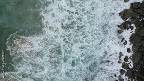 Aerial view over water waves crashing on rocks