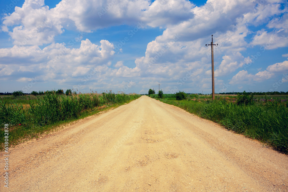 Rural landscape, dirt road through the field in summer