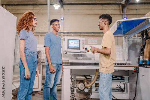 alunos de uma escola técnica Brasileira prestando atenção na explicação do professor durante uma aula prática em uma fábrica photo