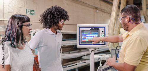 technician from an industry explaining to students from a technical school how the application of a machine works during a class in a factory in Brazil
