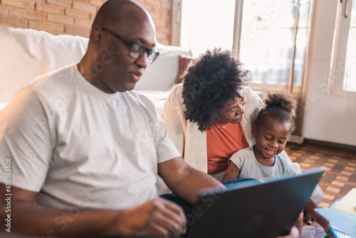 Latin couple sitting on the living room floor of their home paying attention to their daughter while working on the computer