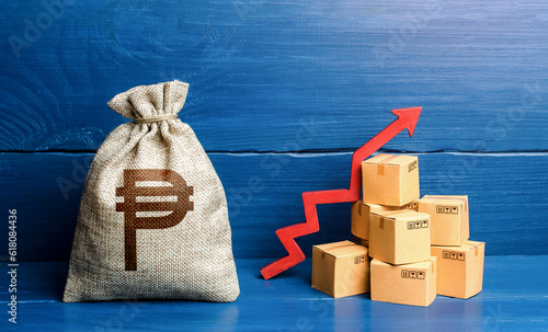 Philippine peso money bag with boxes and up arrow. Income increase, acceleration and growing of economy. High sales. Production rise. Good consumer sentiment and demand for goods. Growing prices photo