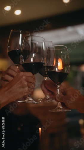 Vertical slow motion video of people clink glasses of wine in a restaurant