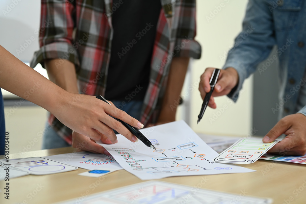 Cropped shot of designer team working on new website wireframe, planning application development for web mobile phone at meeting Cropped shot of designer team working on new website wireframe, planning application development for web mobile phone at meeting