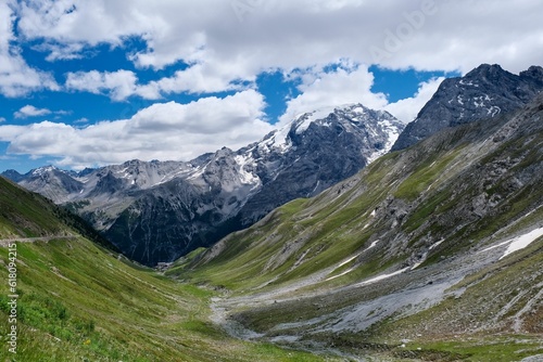 Fototapeta Naklejka Na Ścianę i Meble -  Scenic view of a lush, green valley featuring rolling hills and snow-covered mountains, Italy.