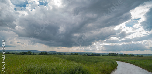 Świętokrzyskie krajobrazy. Deszczowe chmury na niebie . Widoczne pola i łąki w tle Góry Świętokrzyskie ( pasmo Łysogóry i Jeleniowskie ).