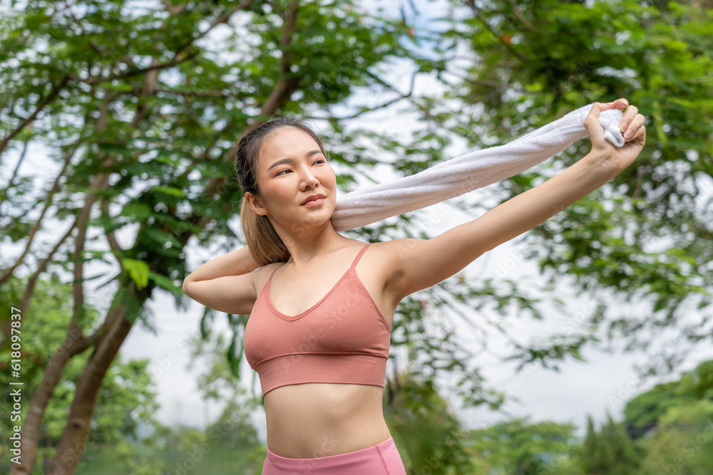 Young attractive Asian woman stretching her arms and legs before her morning exercise run at running track of a local park Young attractive Asian woman stretching her arms and legs before her morning exercise run at running track of a local park